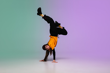 Image showing Girl dancing hip-hop in stylish clothes on gradient background at dance hall in neon light.