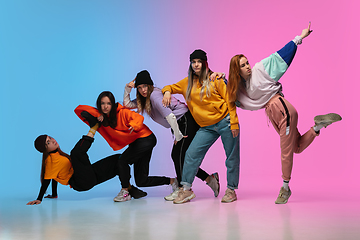 Image showing Group of dancers, boys and girls dancing hip-hop in stylish clothes on gradient studio background in neon light.