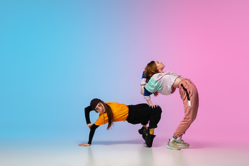 Image showing Girls dancing hip-hop in stylish clothes on gradient background at dance hall in neon light.