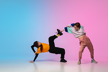 Image showing Girls dancing hip-hop in stylish clothes on gradient background at dance hall in neon light.