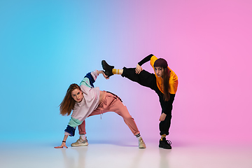 Image showing Girls dancing hip-hop in stylish clothes on gradient background at dance hall in neon light.