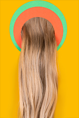 Image showing Female long hair peeking throught circle in yellow background