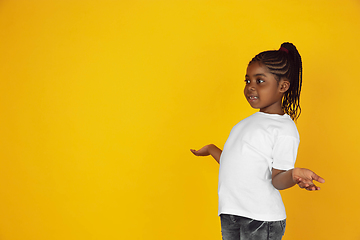 Image showing Little african-american girl\'s portrait isolated on yellow studio background