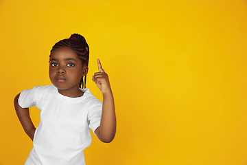 Image showing Little african-american girl\'s portrait isolated on yellow studio background