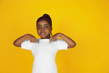 Image showing Little african-american girl\'s portrait isolated on yellow studio background