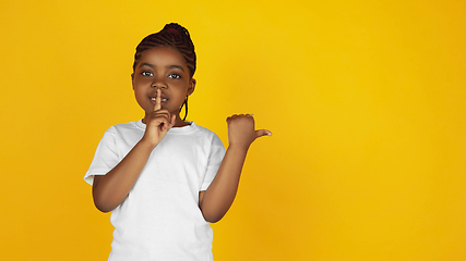 Image showing Little african-american girl\'s portrait isolated on yellow studio background