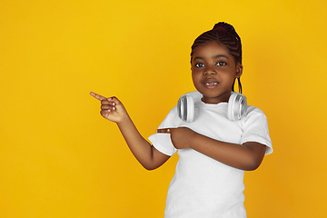 Image showing Little african-american girl\'s portrait isolated on yellow studio background