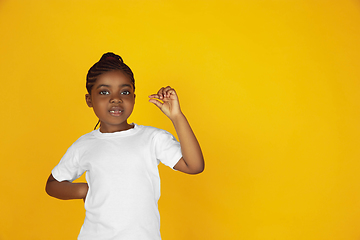 Image showing Little african-american girl\'s portrait isolated on yellow studio background