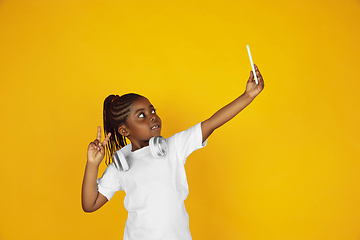 Image showing Little african-american girl\'s portrait isolated on yellow studio background