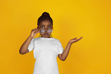 Image showing Little african-american girl\'s portrait isolated on yellow studio background