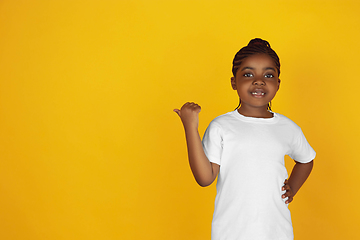 Image showing Little african-american girl\'s portrait isolated on yellow studio background