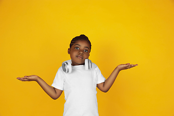 Image showing Little african-american girl\'s portrait isolated on yellow studio background