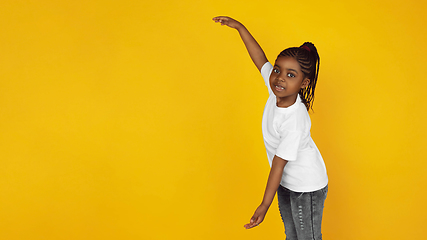 Image showing Little african-american girl\'s portrait isolated on yellow studio background