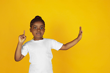 Image showing Little african-american girl\'s portrait isolated on yellow studio background