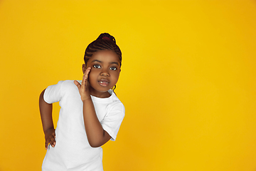 Image showing Little african-american girl\'s portrait isolated on yellow studio background