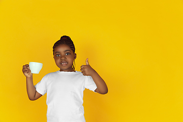 Image showing Little african-american girl\'s portrait isolated on yellow studio background