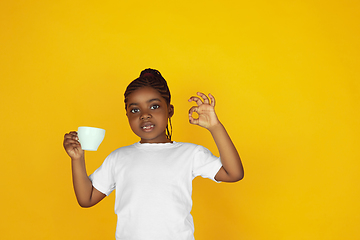 Image showing Little african-american girl\'s portrait isolated on yellow studio background