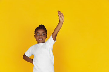 Image showing Little african-american girl\'s portrait isolated on yellow studio background