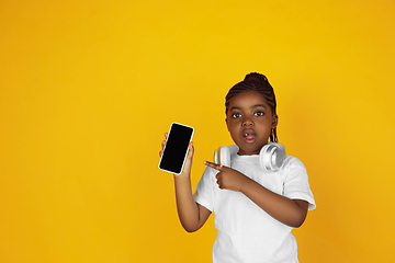 Image showing Little african-american girl\'s portrait isolated on yellow studio background