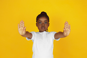 Image showing Little african-american girl\'s portrait isolated on yellow studio background