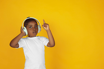 Image showing Little african-american girl\'s portrait isolated on yellow studio background