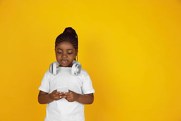 Image showing Little african-american girl\'s portrait isolated on yellow studio background