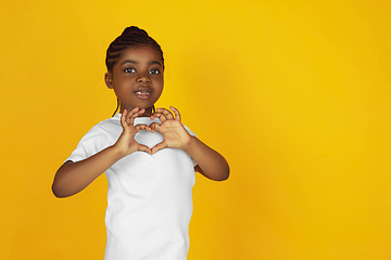 Image showing Little african-american girl\'s portrait isolated on yellow studio background