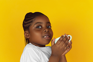 Image showing Little african-american girl\'s portrait isolated on yellow studio background