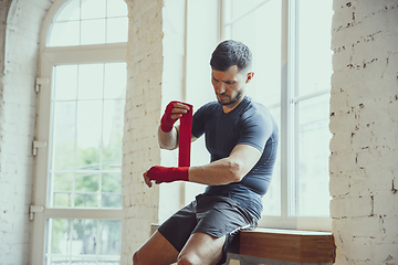 Image showing Young caucasian man training at home during quarantine of coronavirus outbreak, doing exercises of fitness, aerobic. Staying sportive during insulation.