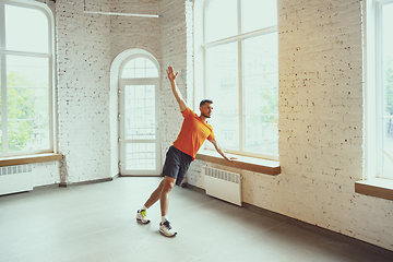 Image showing Young caucasian man training at home during quarantine of coronavirus outbreak, doing exercises of fitness, aerobic. Staying sportive during insulation.