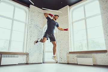 Image showing Young caucasian man training at home during quarantine of coronavirus outbreak, doing exercises of fitness, aerobic. Staying sportive during insulation.