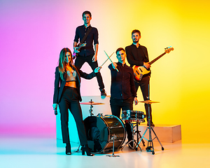 Image showing Young caucasian musicians, band performing in neon light on gradient studio background