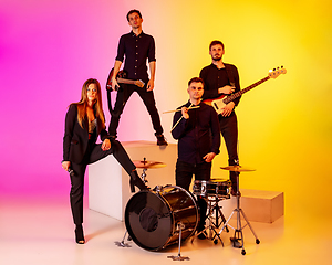 Image showing Young caucasian musicians, band performing in neon light on gradient studio background