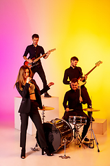 Image showing Young caucasian musicians, band performing in neon light on gradient studio background