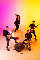 Image showing Young caucasian musicians, band performing in neon light on gradient studio background