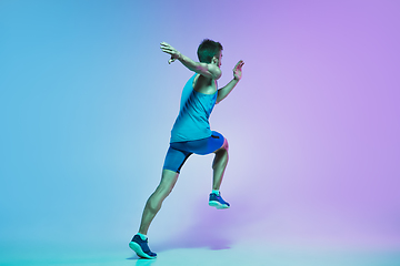 Image showing Full length portrait of active young caucasian running, jogging man on gradient studio background in neon light