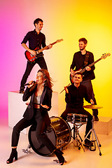 Image showing Young caucasian musicians, band performing in neon light on gradient studio background