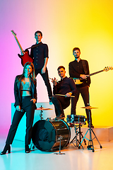 Image showing Young caucasian musicians, band performing in neon light on gradient studio background