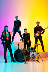 Image showing Young caucasian musicians, band performing in neon light on gradient studio background