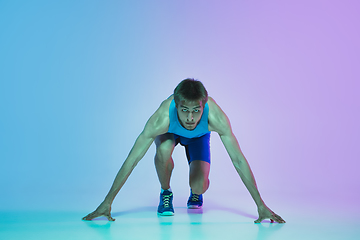 Image showing Full length portrait of active young caucasian running, jogging man on gradient studio background in neon light