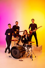 Image showing Young caucasian musicians, band performing in neon light on gradient studio background