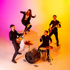 Image showing Young caucasian musicians, band performing in neon light on gradient studio background