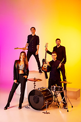 Image showing Young caucasian musicians, band performing in neon light on gradient studio background