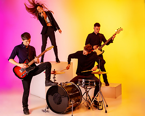 Image showing Young caucasian musicians, band performing in neon light on gradient studio background