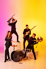 Image showing Young caucasian musicians, band performing in neon light on gradient studio background
