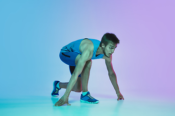 Image showing Full length portrait of active young caucasian running, jogging man on gradient studio background in neon light