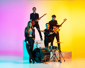 Image showing Young caucasian musicians, band performing in neon light on gradient studio background