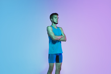 Image showing Full length portrait of active young caucasian running, jogging man on gradient studio background in neon light