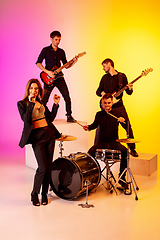 Image showing Young caucasian musicians, band performing in neon light on gradient studio background