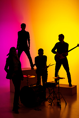 Image showing Young caucasian musicians, band performing in neon light on gradient studio background